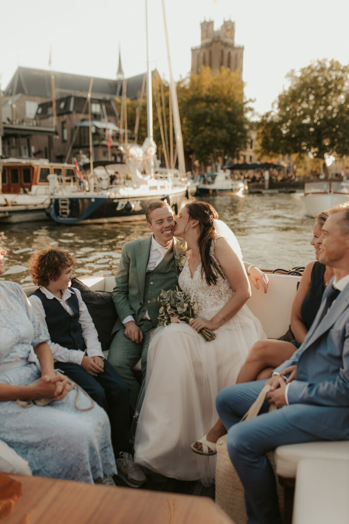 Bruid geeft kusje op wang bruidegom terwijl ze varen met boot in Dordrecht